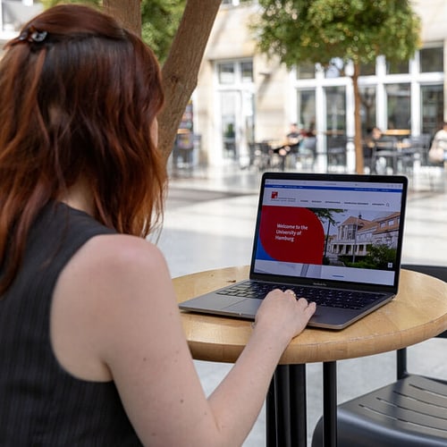 Eine Person blickt auf einen Laptop, der die Startseite der UHH zeigt.